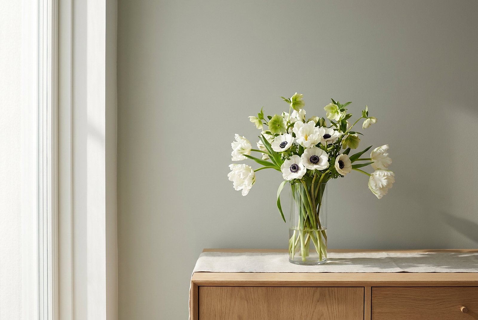 White tulips, anemones and hellebores in a glass vase